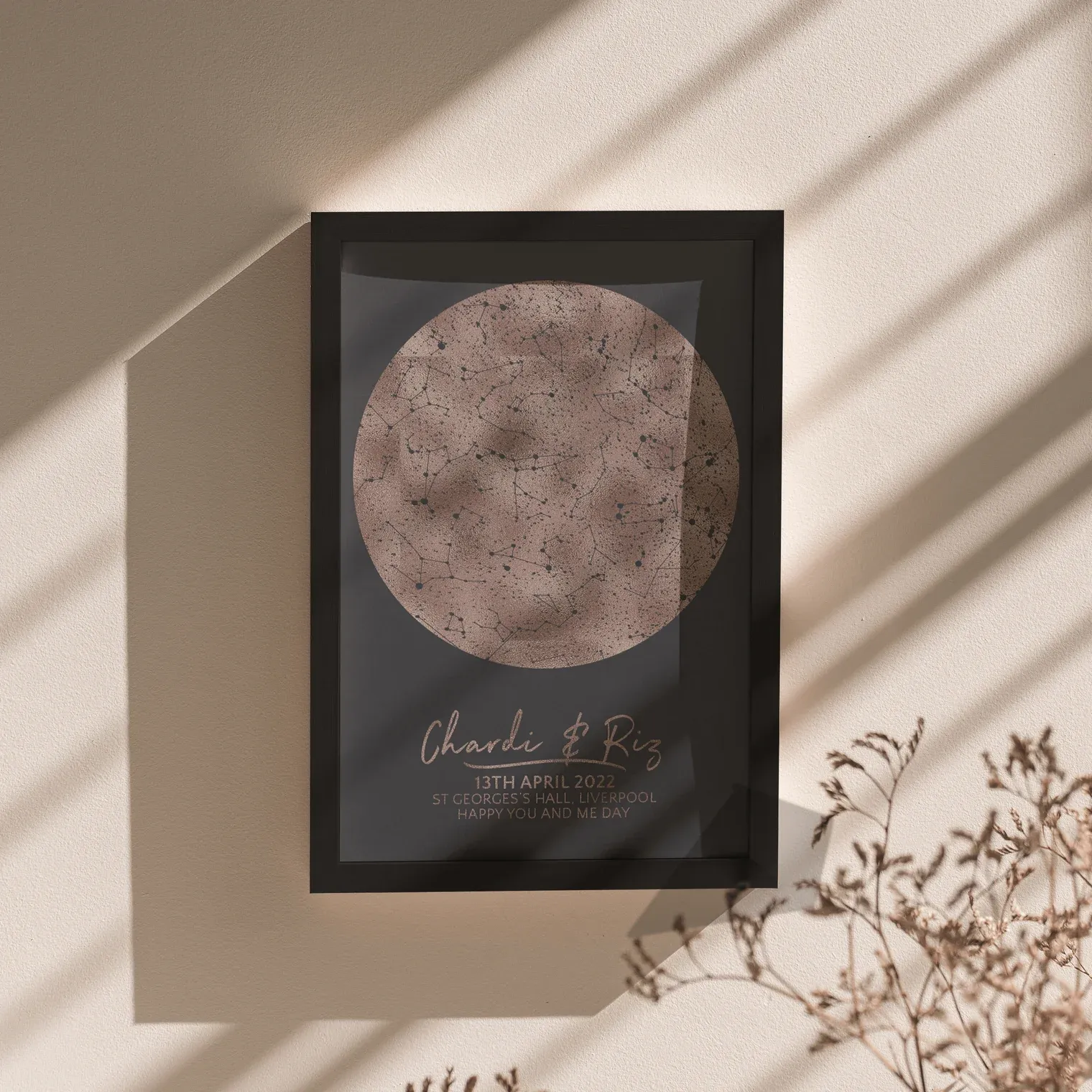 Rose gold circular pattern metallic foil print in a dark frame on a surface with light casting shadows